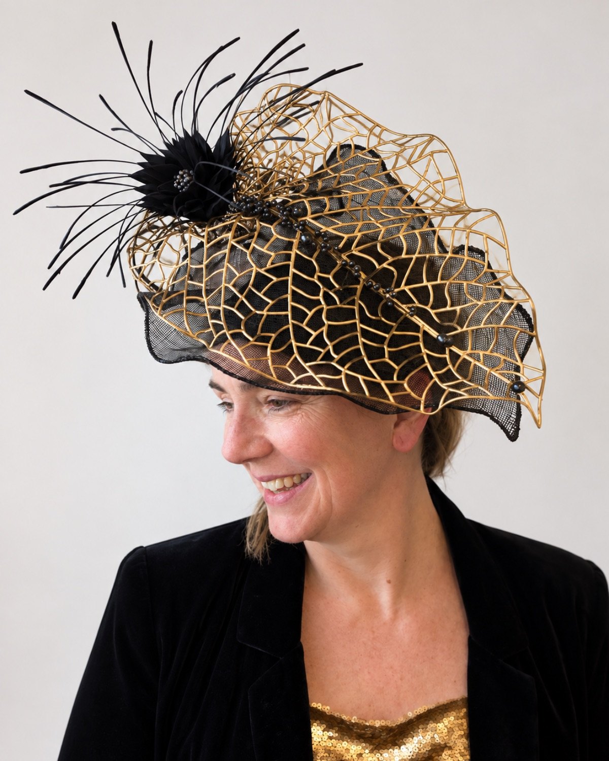 Bespoke black and gold occasion hat — sinamay with gilded lattice and feather flower, handmade by Anna John Designs, New Zealand