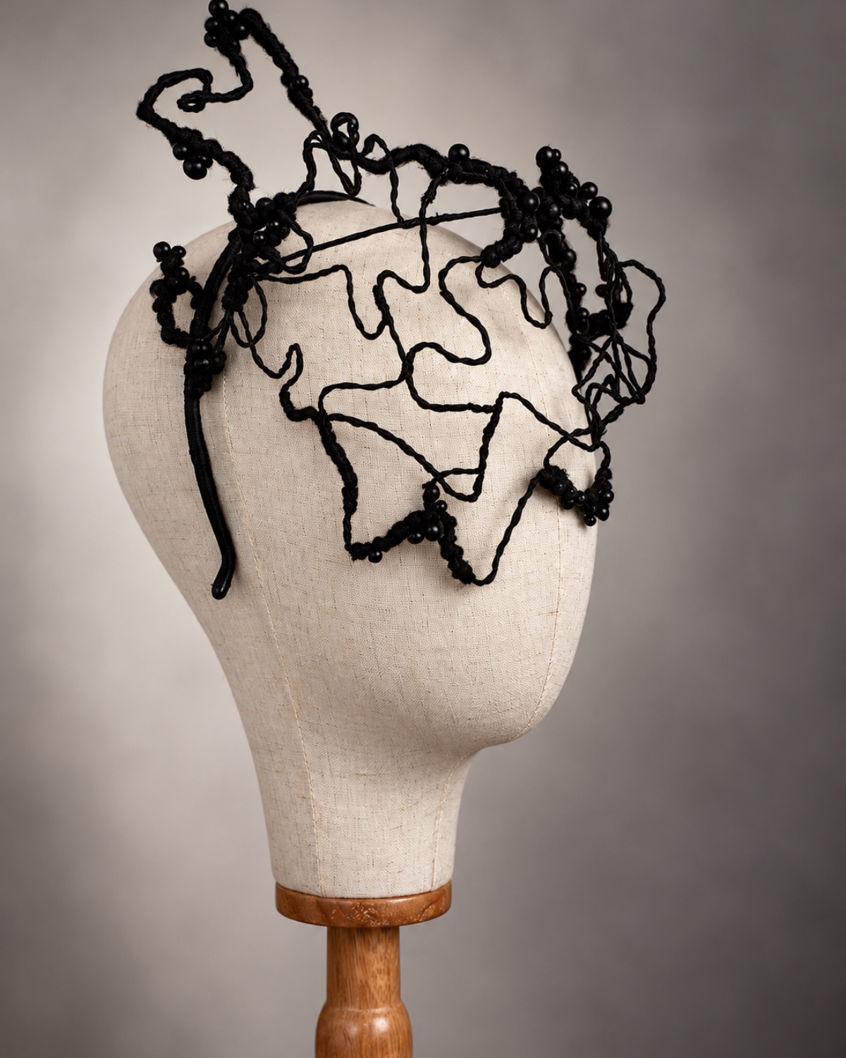 Bespoke black wire sculptural headpiece, three-quarter view — hand-twisted wire wrapped in thread with clusters of jet beads, handmade by Anna John Designs, New Zealand